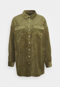 Camicia in corduroy verde oliva con chiusura a bottoni, due tasche sul petto e colletto standard. Vestibilità rilassata con maniche lunghe e tessuto strutturato.