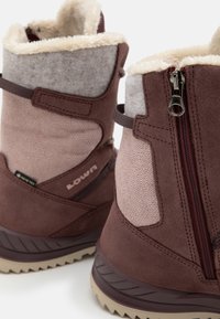 Stivali alla caviglia in suede marrone e tessuto con foderato in pelliccia, zip laterale e suola testurizzata. Presentano dettagli rosa e cinturini regolabili.
