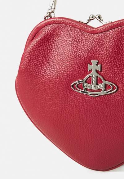 Red leather heart-shaped handbag with a textured surface, featuring a silver crown and planet emblem as the main accent.