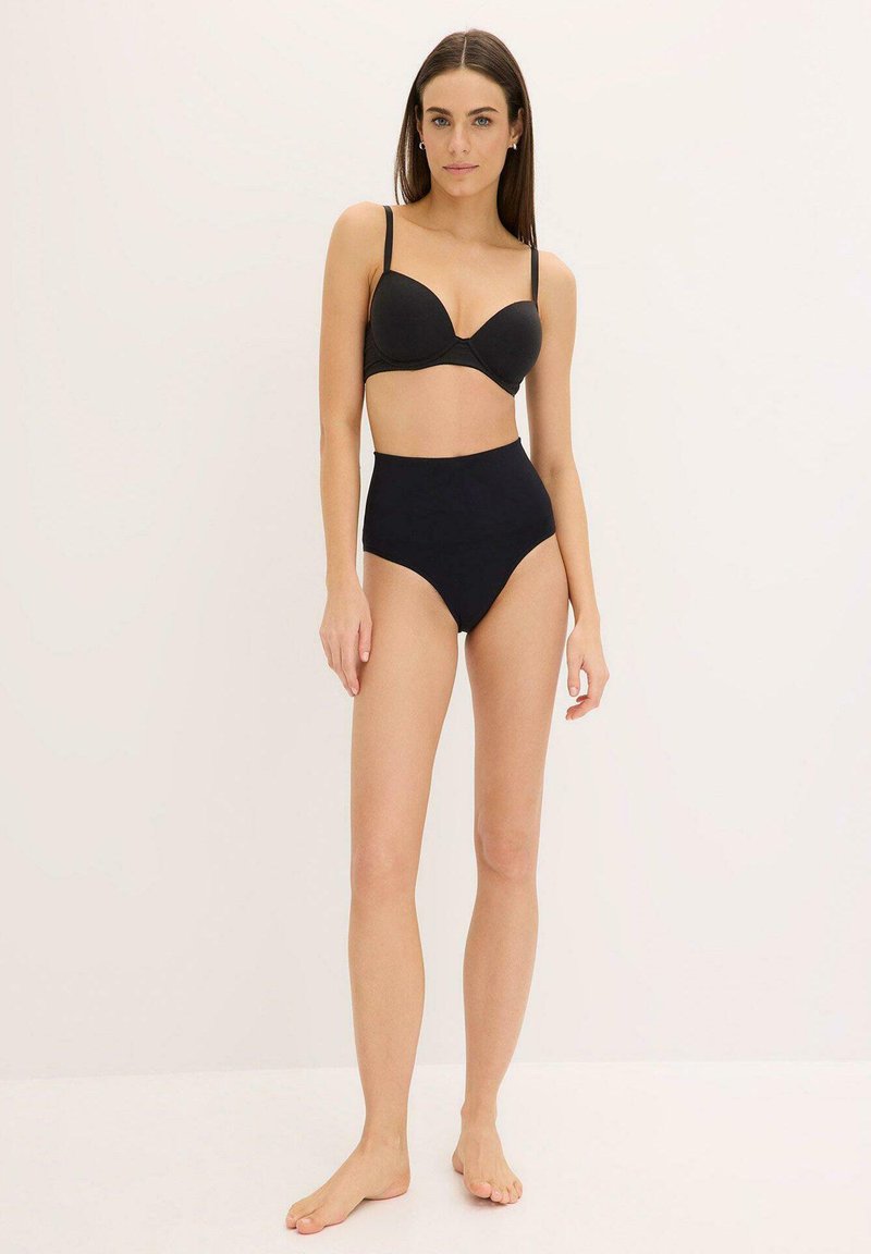 Soutien-gorge noir rembourré avec armatures et bretelles réglables, associé à des culottes taille haute noires en tissu lisse.