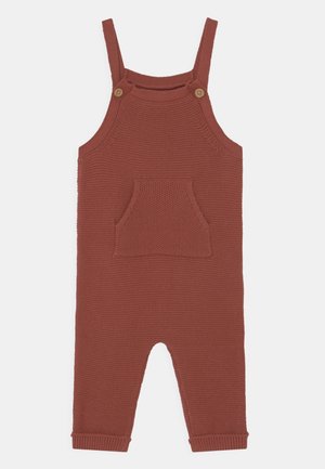 Barboteuse tricotée couleur rouille pour bébé avec bretelles à boutons et poche avant, conçue pour la chaleur et le confort.