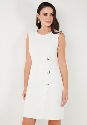 White sleeveless dress with a round neckline, featuring three decorative buckle accents on the front and a fitted silhouette.