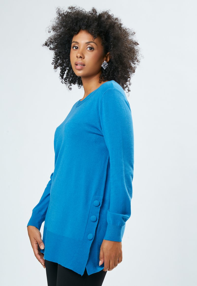 Blaues langärmliges Sweater aus weichem Material, mit Rundhalsausschnitt und drei dekorativen Knöpfen auf der linken Seite.