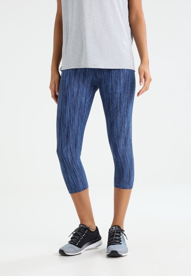 Blue capri leggings with a textured pattern, made from stretchy material. Paired with a gray shirt and black athletic shoes.