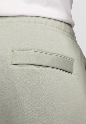 Hellgrüne Sweatpants mit einer Rückentasche und rechteckiger Klappe, aus weichem Baumwollstoff mit glatter Textur.