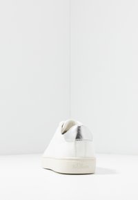 Weiße Sneaker mit einem glatten Lederobermaterial, silbernem Akzent an der Ferse und einer strukturierten Gummisohle. Beinhaltet ein minimalistisches Design mit Logodetail.