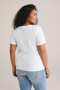Hvid kortærmet T-shirt med rund hals, glat tekstur og tætsiddende silhuet, parret med lyseblå jeans.