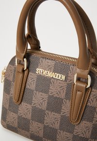 Borsa a tracolla marrone con motivo, dotata di due manici corti; presenta un logo del marchio dorato e una chiusura con zip con finitura testurizzata.