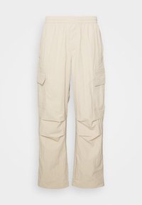 Pantaloni cargo beige con vita elasticizzata, due tasche laterali e una vestibilità comoda con una texture increspata.