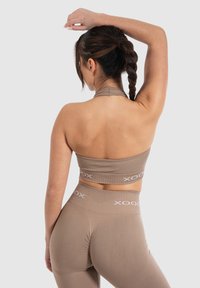 Bruine geribbelde crop top en high-waisted leggings met witte logo-accenten, ontworpen voor een strakke pasvorm. Zachte textuur, sportief patroon.