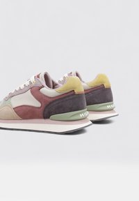 Zapatillas multicolores que combinan materiales de ante y malla, con tonos de púrpura, beige y mostaza. Cintas blancas y logotipo en el talón.