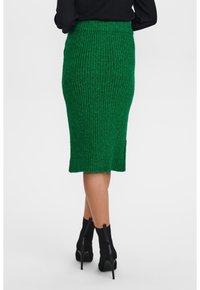 Grüne gerippte knielange Rock mit enganliegendem Bund und einem Schlitz am Saum, kombiniert mit schwarzen Ankle-Boots mit Absatz.