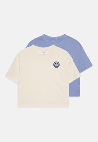 Medvilniniai T-shirts, vienas grietinėlės spalvos su šypsenėlės siuvinėjimu, ir vienas šviesiai mėlynas, abu trumpomis rankovėmis ir laisvu siluetu.