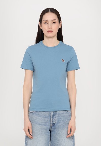 Tricou din bumbac albastru, cu guler rotund și mâneci scurte, având un mic design brodat cu o zebră pe partea stângă a pieptului.