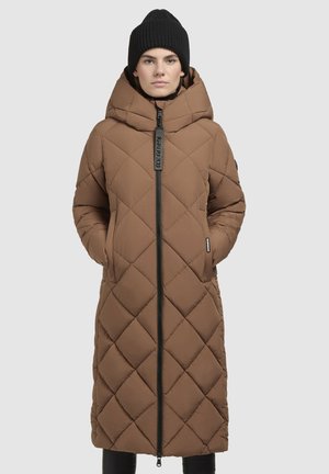 Barna steppelt hosszú kabát magas gallérral, cipzáras záródással és két oldalsó zsebbel. Fekete sapkával párosítva a melegebb időjárásért.