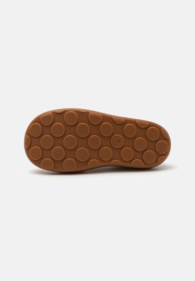 Rubber shoe sole featuring a circular tread pattern, brown color, and rounded edges, designed for traction and durability.