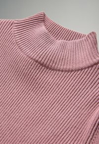 Geribbelde gebreide turtleneck trui in lichtroze, met een hoge kraag en een gestructureerde stof. Focus op de zachte, verticale ribbels van de kraag.