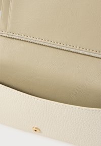Off-white faux leather bag interior with a textured surface, featuring a beige lining and a gold snap closure.