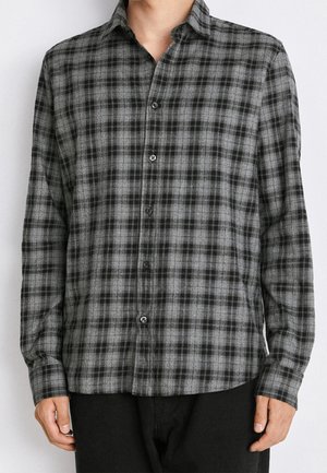 Camisa de botón en patrón de cuadros gris y negro, fabricada en una tela suave. Cuenta con un cuello, mangas largas y puños de un solo botón.