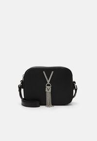 Black textured rectangular crossbody bag with adjustable strap and silver V-shaped metal ornament with chain tassels.