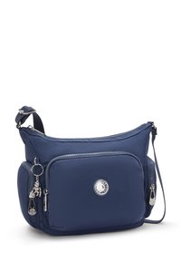 Mørkeblå nylon crossbody taske med en frontlomme med lynlås, sølvhardware og et rundt logo; har en aftagelig charm og justerbar strop.