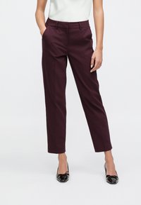 Pantalon sur mesure bordeaux à coupe slim, doté de poches latérales et d'une texture lisse. Associé à des chaussures en cuir verni noir.