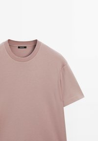 T-shirt di cotone rosa chiaro con scollo rotondo, maniche corte e texture liscia. Presenta un'etichetta del marchio all'interno del colletto.