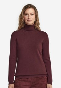 Burgundy polokrage tröja med långa ärmar, ribbade muddar och nederkant. Tillverkad av mjukt stickat tyg som visar en jämn och slät textur.