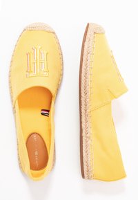 Espadrilles jaunes à enfiler avec une semelle en jute tissée. Présentent un logo brodé proéminent, une texture en coton lisse et des accents de couture contrastés.