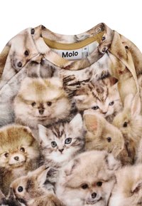 Felpa caratterizzata da un tessuto morbido e texture con una palette di colori tenui. Presenta un motivo con volti di diversi animali, principalmente gattini e cuccioli.