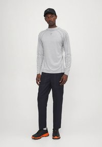 Gray long-sleeve athletic shirt with raglan sleeves, dark navy pants, and black sneakers with orange accents. Simple, functional design.