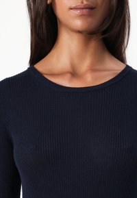 Haut en tricot côtelé marine avec un col rond et une coupe ajustée, mettant en valeur un tissu texturé avec des rayures verticales.