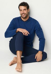 Mans långärmad marinblå randig topp med matchande marinblå byxor, med rund halsringning och mjuk, slät textur.