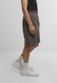 Gray cotton shorts with an elastic waistband, knee-length cut, paired with white sneakers and crew-length socks.