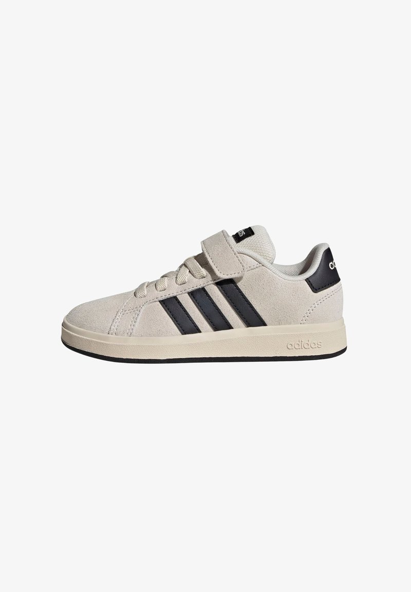 Beige lavtop Adidas sneaker med sorte striber, snørebånd, en velcro-rem og en sort hælfane.