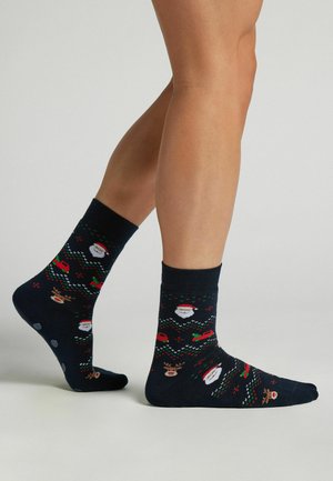 Námořnické ponožky s vánočními vzory, které zobrazují Santy, soby a vánoční stromy. Směs bavlny, kotníková výška, žebrovaný lem, jemná textura.