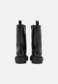 Bottes cheville en cuir noir avec une finition brillante, bout arrondi, fermeture éclair à l'arrière et semelle en caoutchouc épaisse pour la traction.