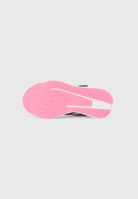 Semelle de sneaker avec une base en caoutchouc rose présentant un motif texturé. Le haut est blanc, avec des lignes grises accentuant l'arrière.