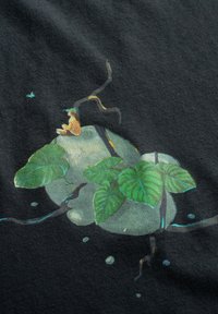 Zwarte stof met een bedrukte print die groene bladeren, abstracte vormen en een kleine bruine kikker toont, omringd door organische elementen en zachte texturen.