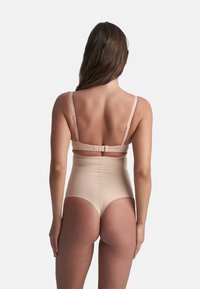 Costume da bagno beige a vita alta con spalline regolabili e chiusura a gancio. Texture liscia e design minimalista, adatto per nuotare o prendere il sole.