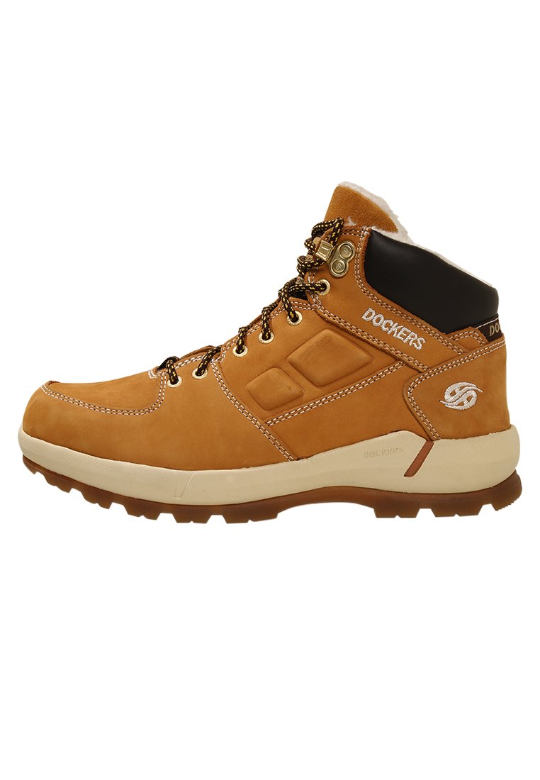 Botte de randonnée en cuir tan avec un col rembourré noir, des œillets en metal et des coutures contrastantes. Dispose d'une semelle en caoutchouc texturée pour une meilleure adhérence.