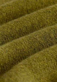 Textured olive-green fabric with a soft, fuzzy surface. The material features a ribbed pattern, creating a wavy appearance.