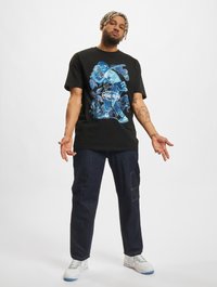 Black cotton t-shirt featuring a colorful graphic print depicting a baseball player, paired with dark denim jeans and white sneakers.