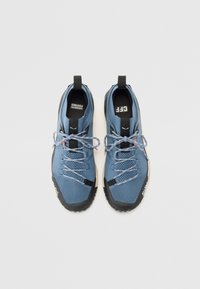 Baskets en maille bleue avec des semelles en caoutchouc noires. Dotées de lacets gris, d'un col rembourré et d'une languette à l'arrière. Logo de la marque bien visible sur le côté.