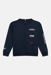 Granatowa bluza z długim rękawem i okrągłym dekoltem, z nadrukowanymi białymi i czerwonymi logo Tommy Hilfiger na klatce piersiowej i rękawach.