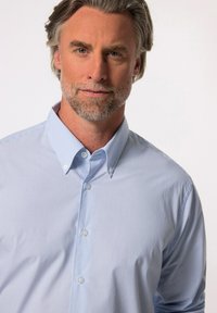 Camicia di colore azzurro chiaro con righe bianche, dotata di colletto alla francese e maniche lunghe. Il tessuto sembra liscio e leggero.