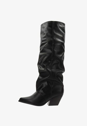 Botas altas de cuero negro con punta afilada, caña caída y tacón de bloque en ángulo sobre un fondo blanco.