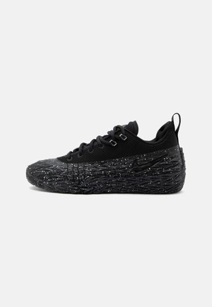 Czarny niskoprofilowy sneaker z teksturowaną, nakrapianą podeszwą, siateczkową cholewką, wiązaniem z przodu i pętlą do ściągania na pięcie na białym tle.