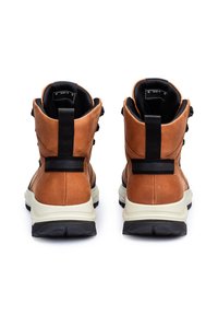 Bottes en cuir marron avec un intérieur noir, présentant un design à cheville haute, une semelle contrastante, des sangles noires et une finition texturée.