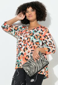 Top colorato con stampa animalier, a scollo a V, maniche 3/4, nei colori pesca, nero e turchese. Abbinato a una clutch a righe zebrate in bianco e nero.